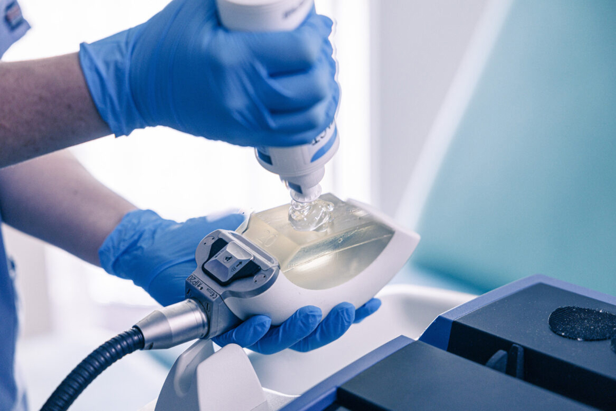 A clinician in blue gloves sets up a shockwave device