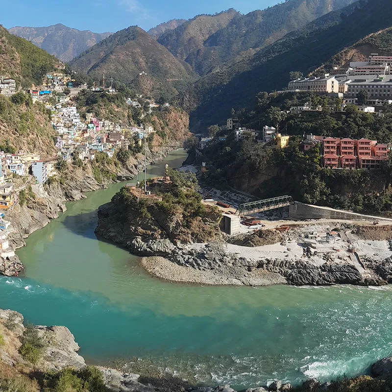 A small town on either bank of a blue river in a valley amongst mountains