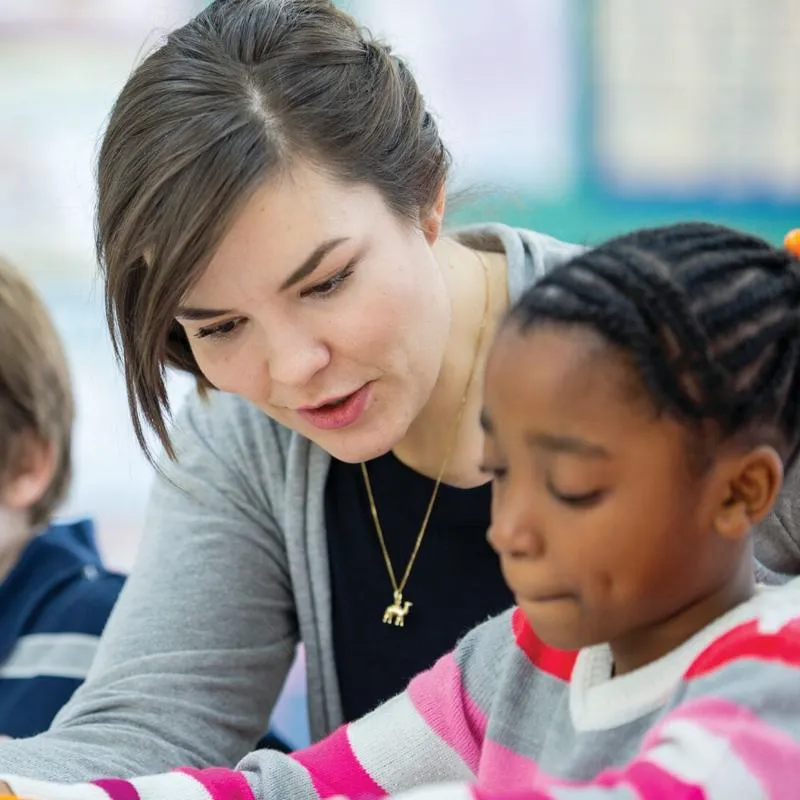 A teacher helps a school student with work in a classroom