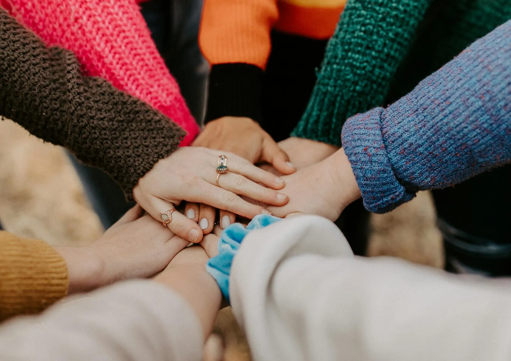 A group of people a overlay hands in the centre of a circle