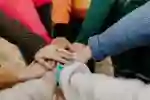 A group of people a overlay hands in the centre of a circle