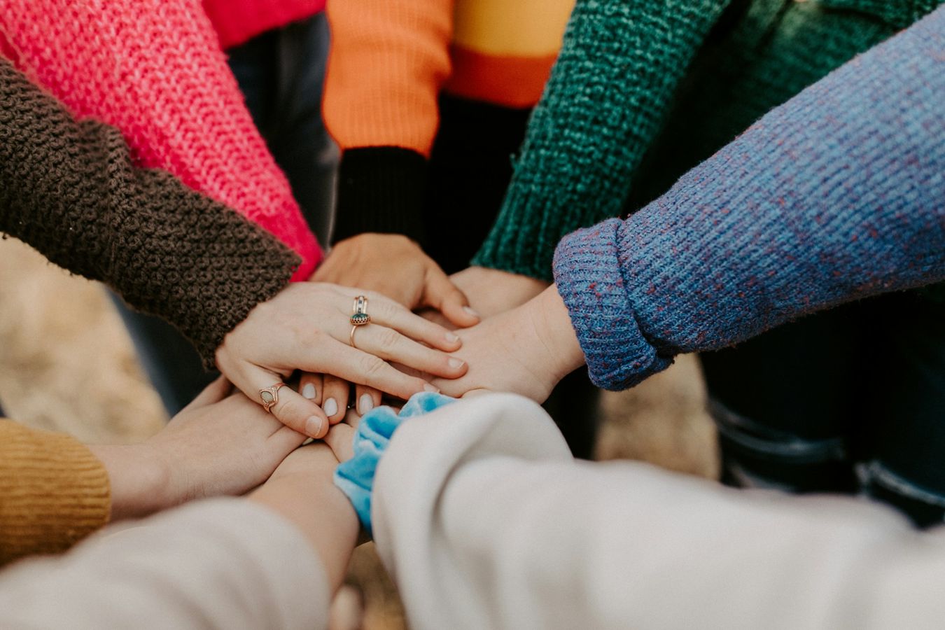 A group of people a overlay hands in the centre of a circle