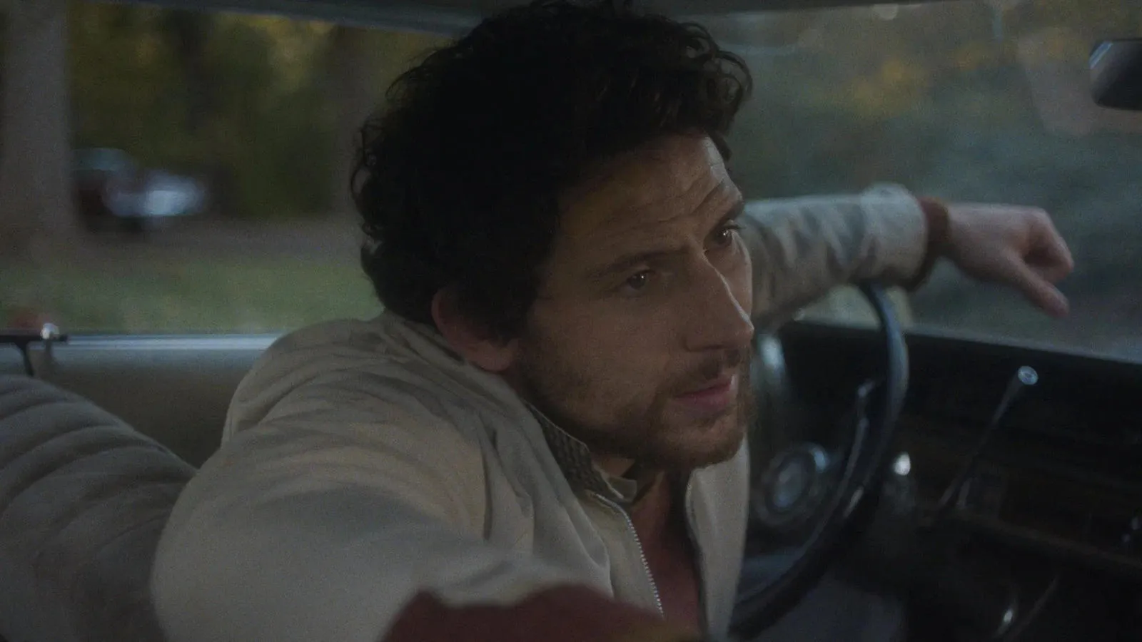 Josh O'Connor behind the wheel of a car in a film still from The Mastermind