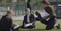 Teacher and students with clipboards on their school field