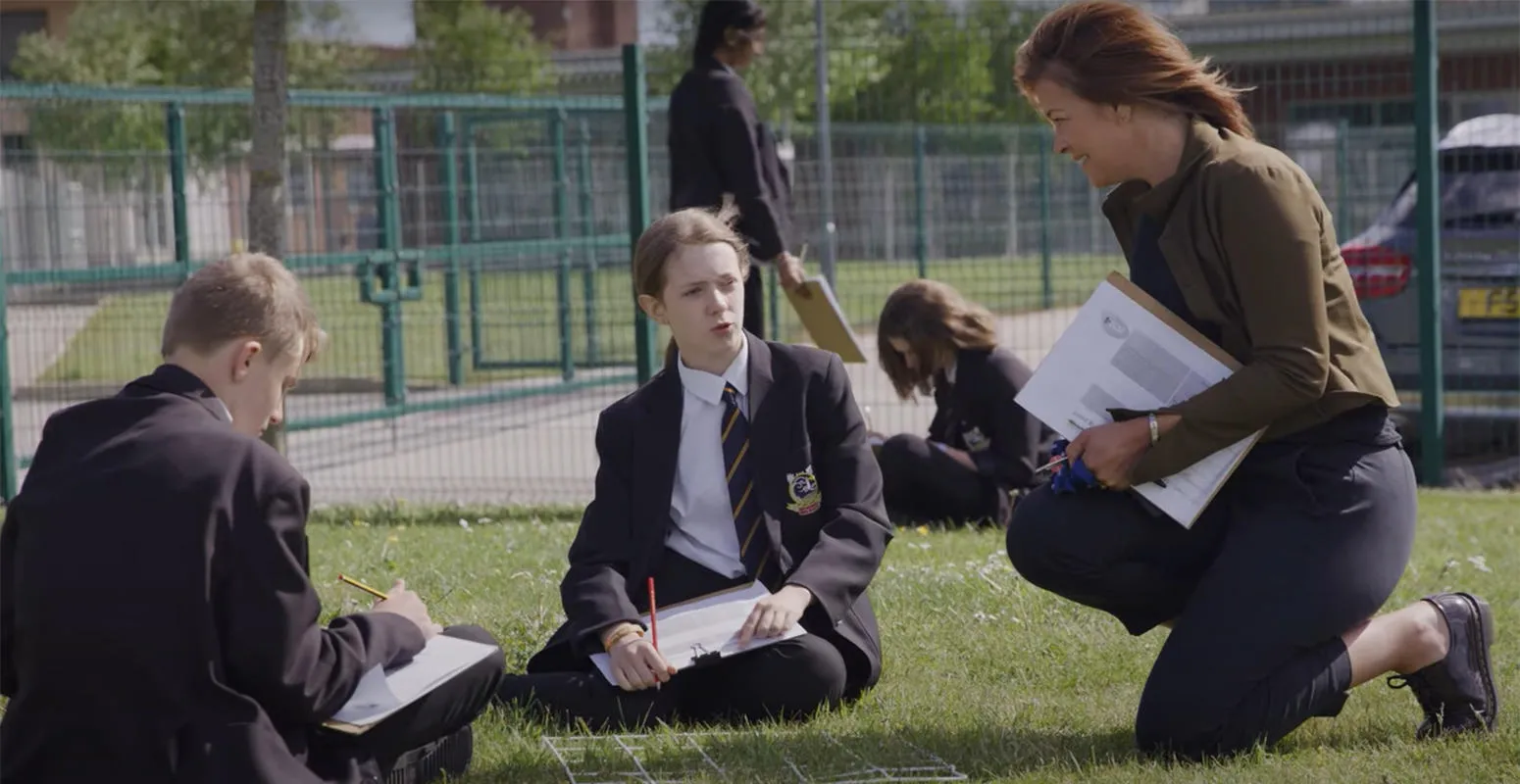 Teacher and students with clipboards on their school field
