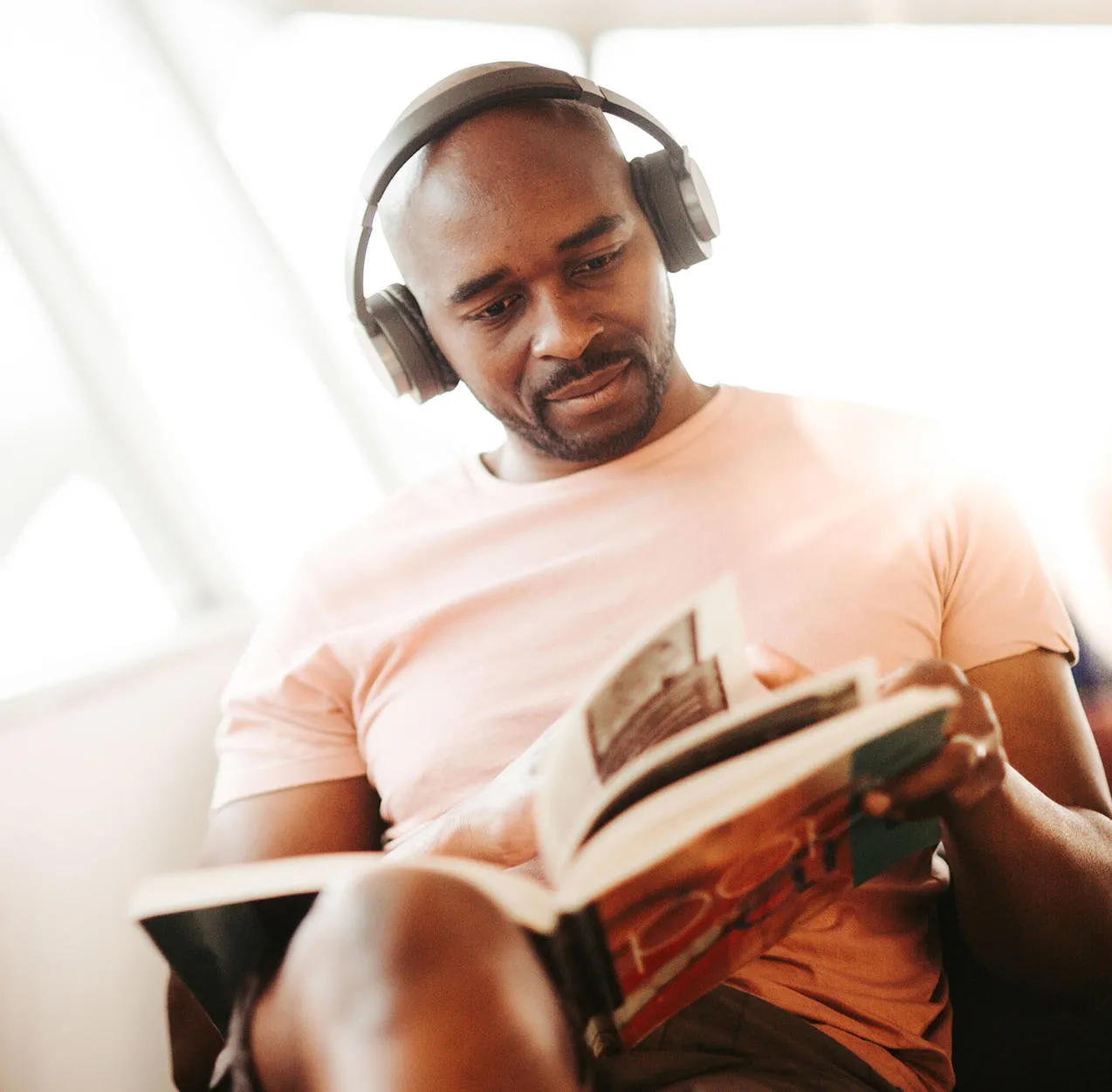 Student with headphones sits and reads a book