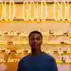 A student stands in front of gold illuminated neon writing, part of an artwork in Ferens Art Gallery