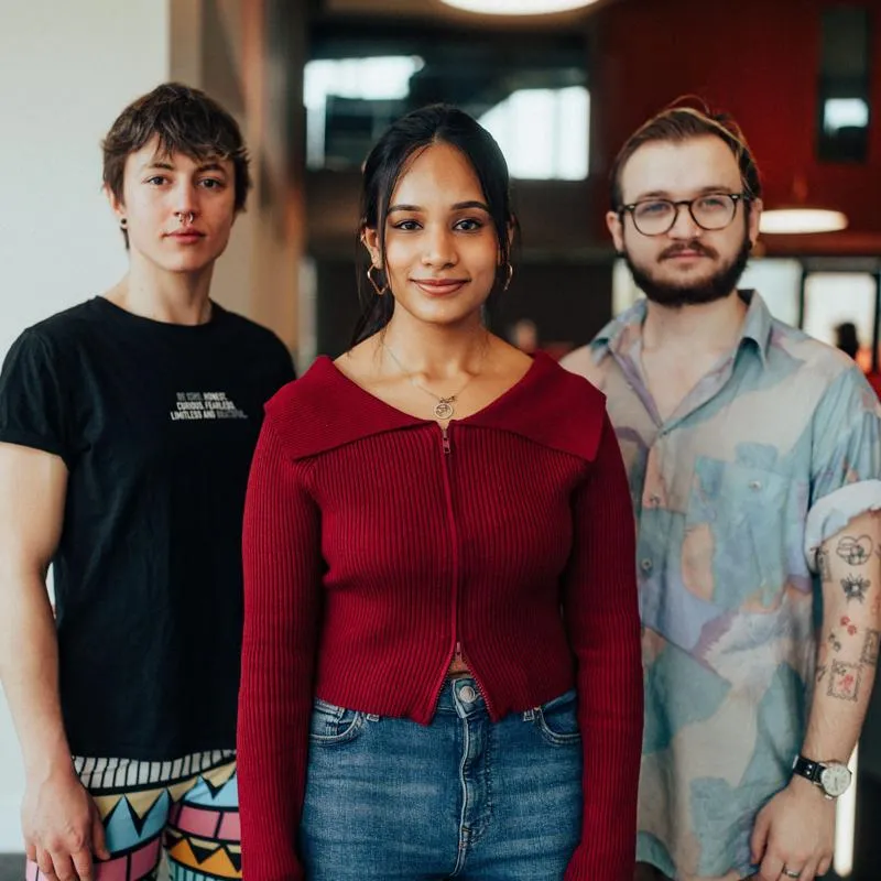 Three students standing confidently in the Allam Medical Building