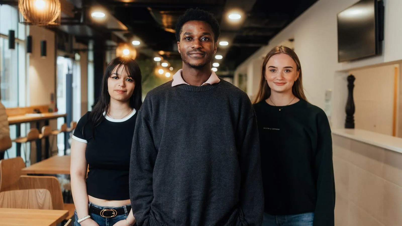 Three students posing in dimly lit room