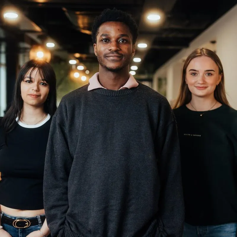 Three students smiling confidently in one of the University's eateries
