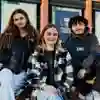 3 students looking to camera in front of university library