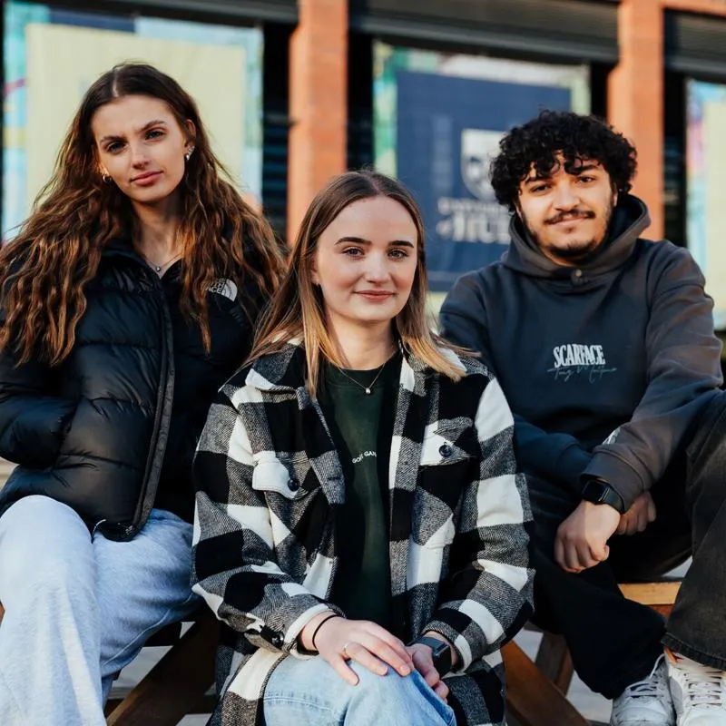 Three University of Hull students sat outside on campus