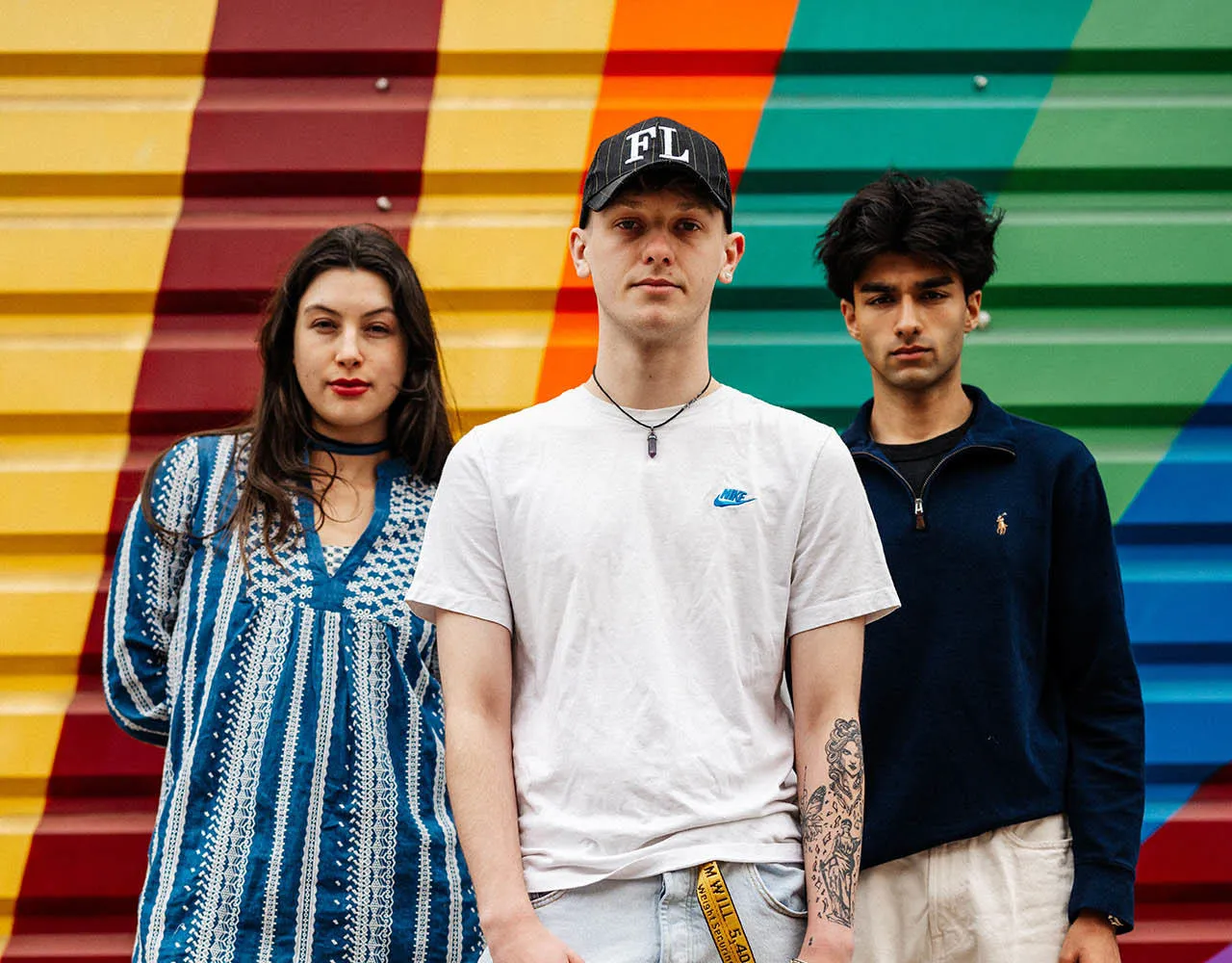 3 students standing in front of graffiti covered shop shutter