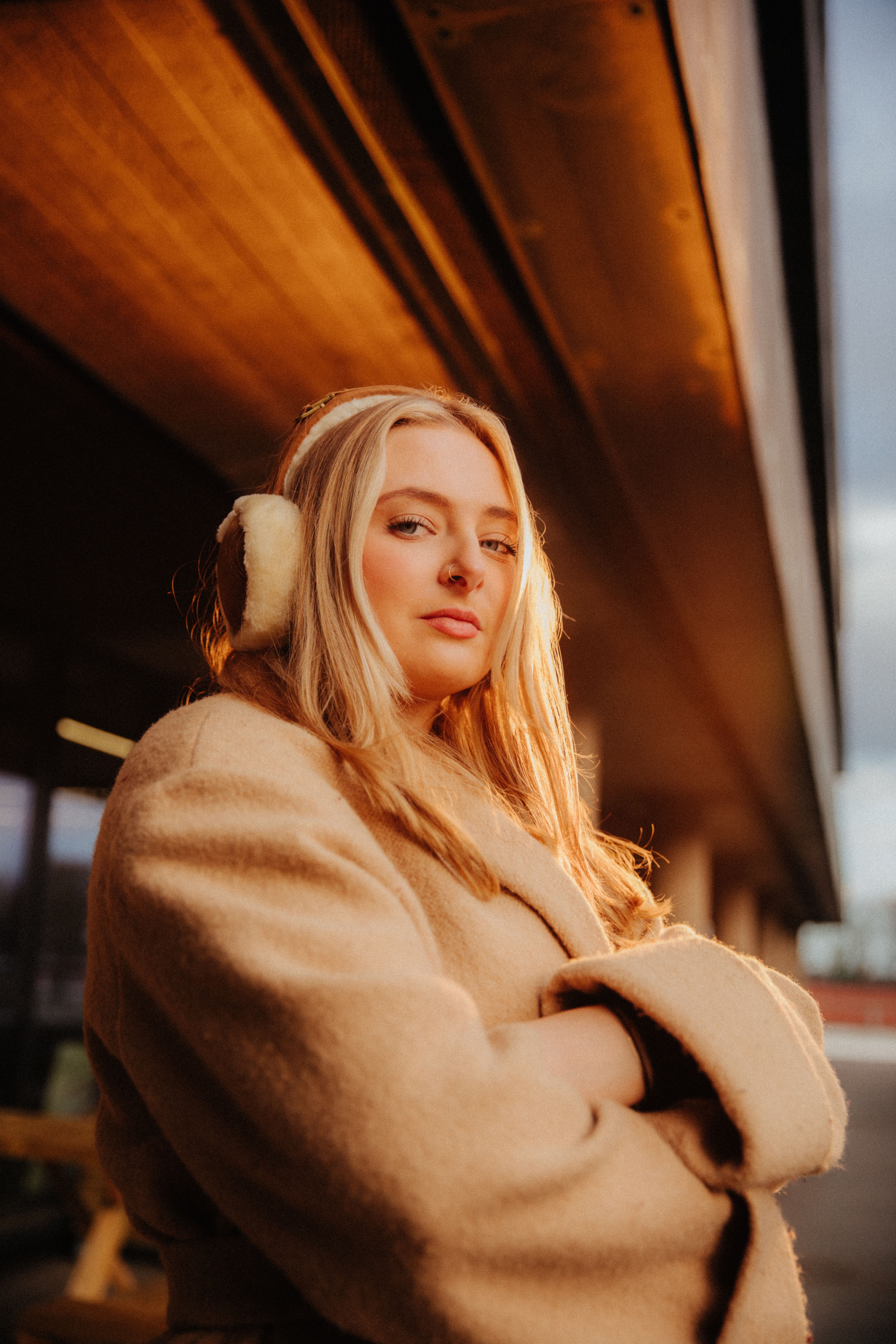 Student Annabel Swallow stand outside the students' union wearing ear muffs