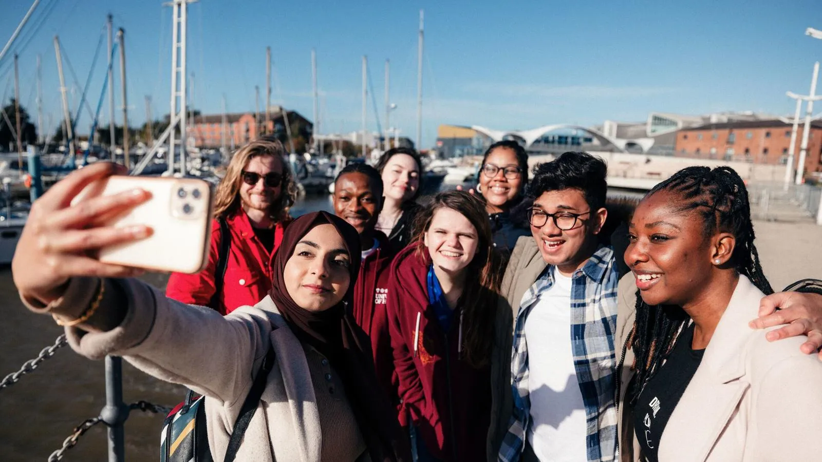 group of friendly students on the harbour taking a selfie together