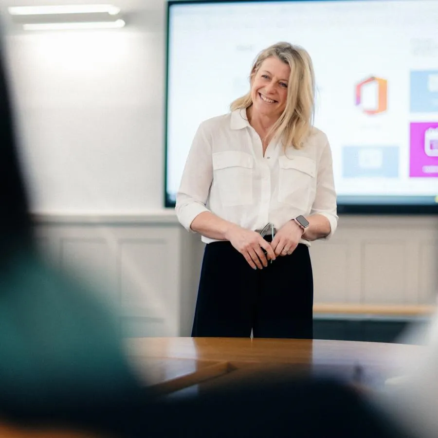 Lecturer stood smiling at the front of a classroom