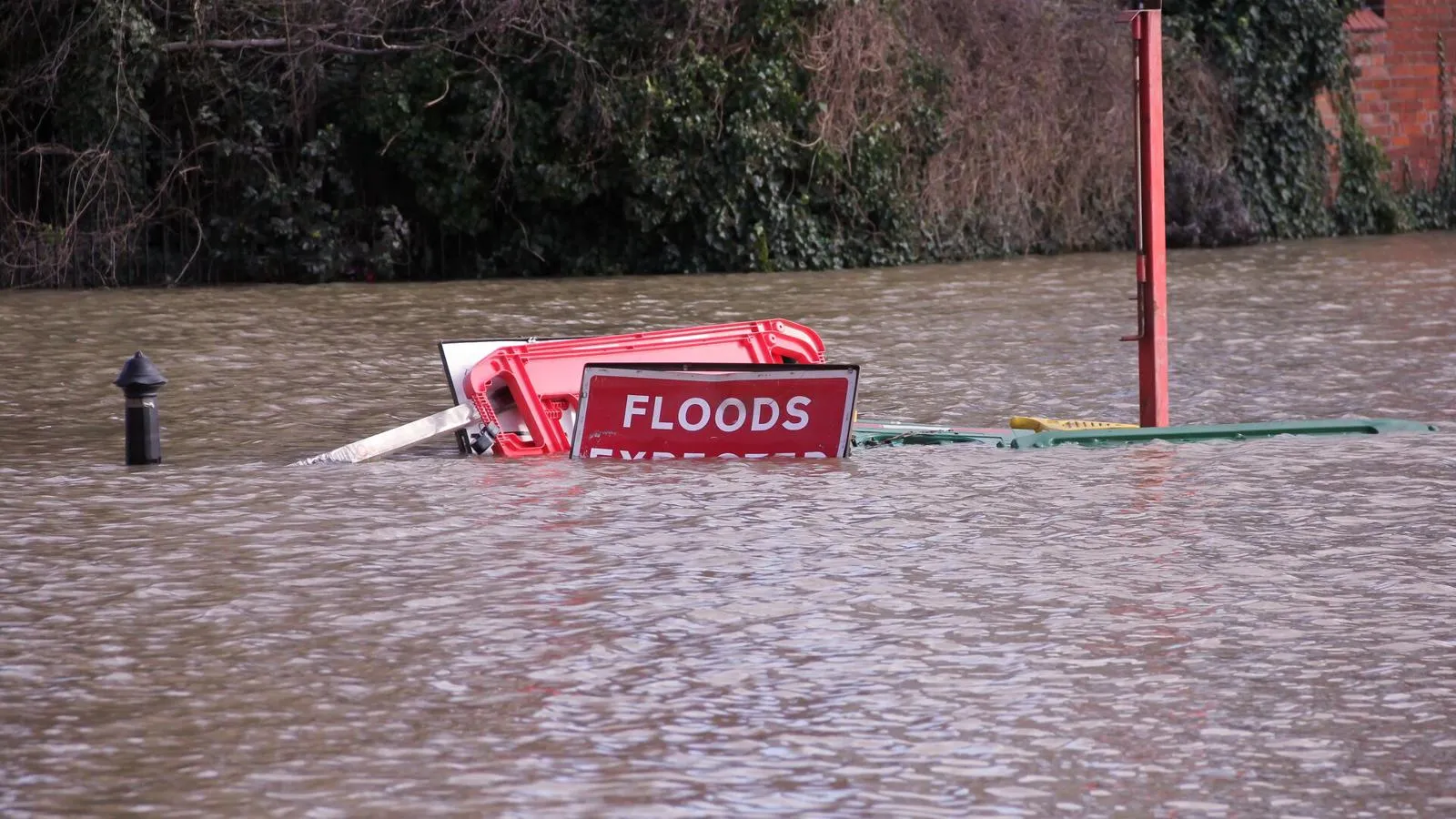 A floods expected sign submerged in water.