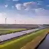 Wind turbines and solar panels in fields next to a river.