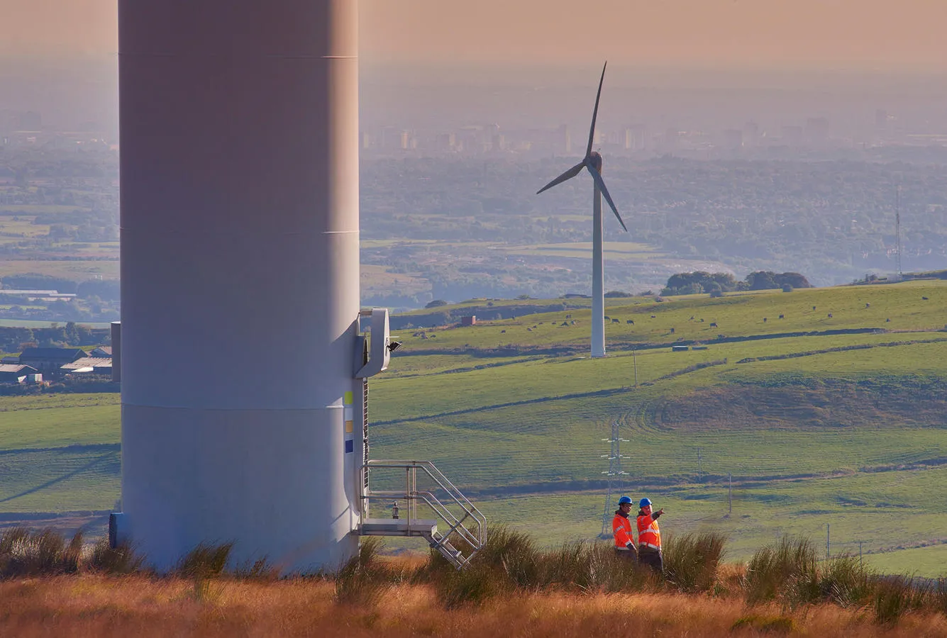 Two people pictured at the base of a wind turbine