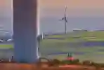 Two people pictured at the base of a wind turbine