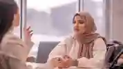Two students chatting next to laptops