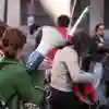 A woman in a green jumper grips a megaphone in a crowd of people during a peaceful protest on a busy street