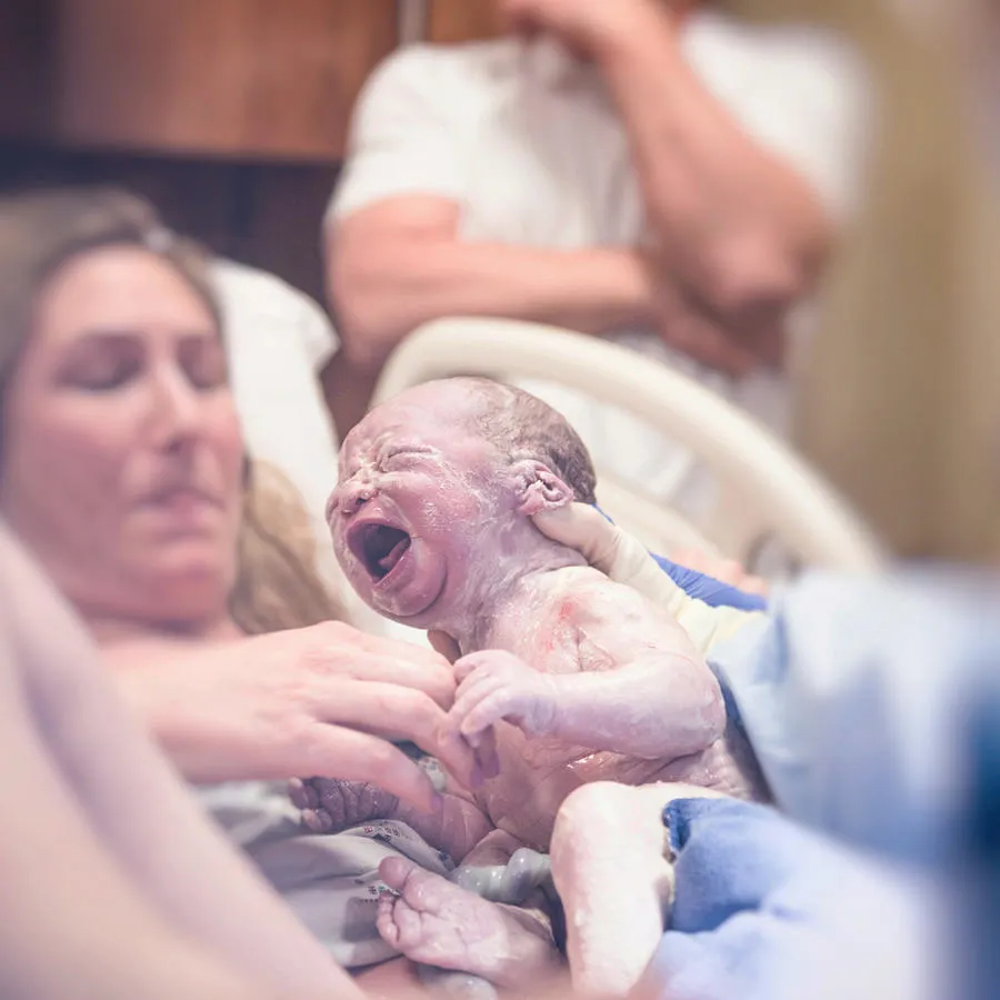 New born baby being handed to mother