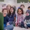 Children sitting on a mat in front of a student