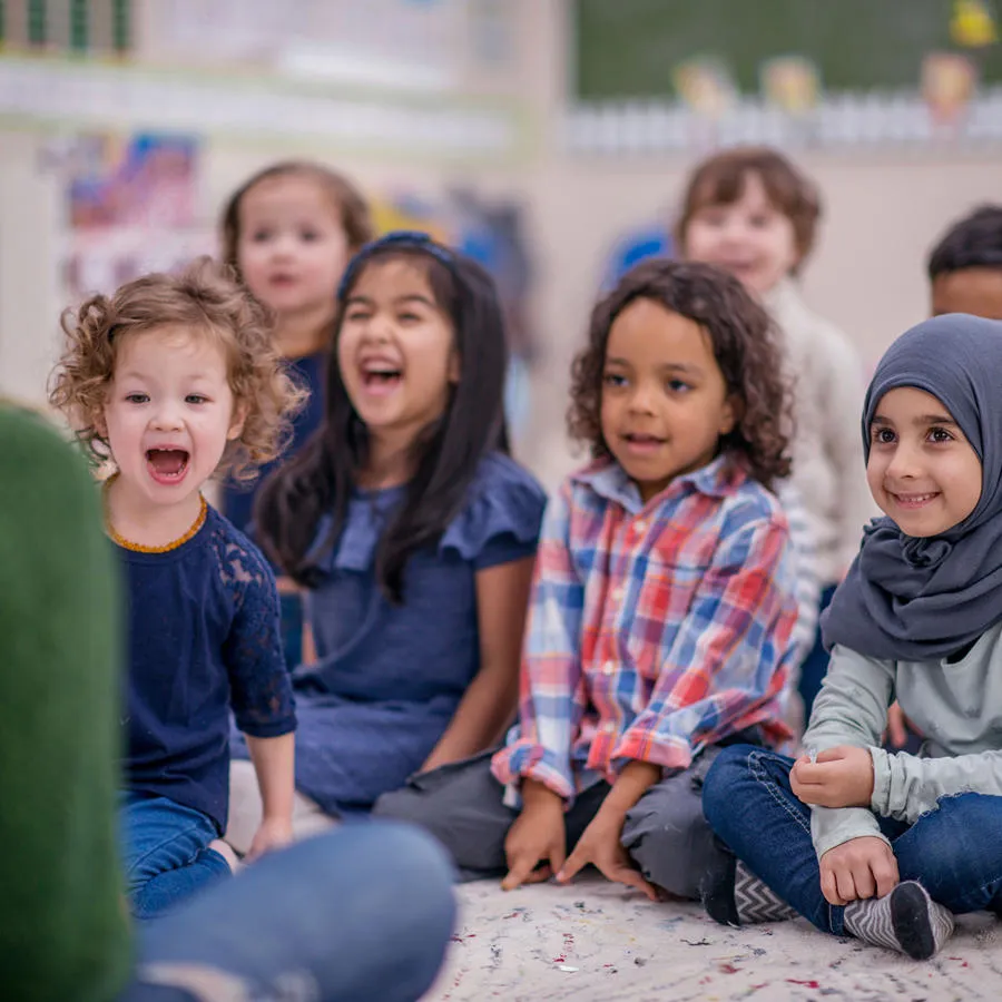 Children sitting on a mat in front of a student