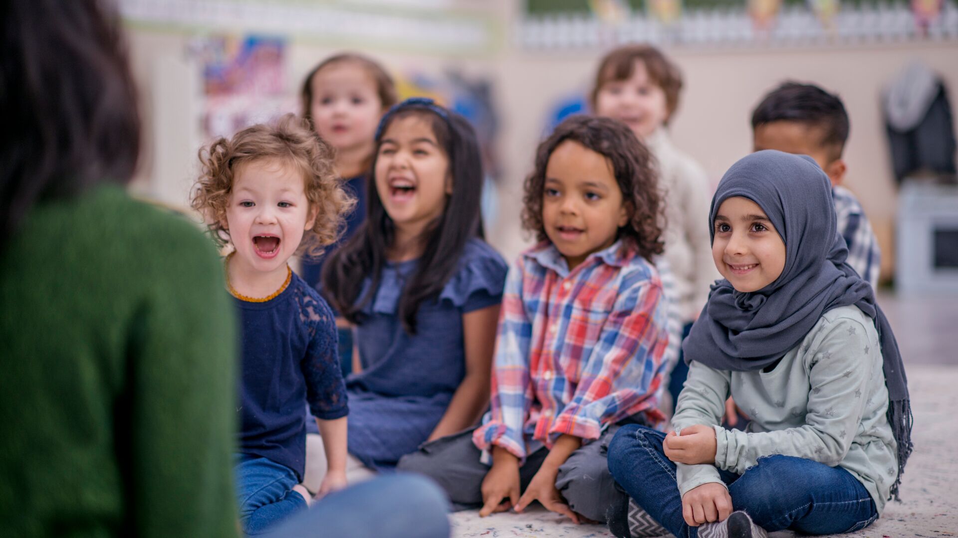 children sat on a playmat together listening to a story