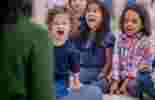 children sat on a playmat together listening to a story