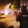 A police officer holding a riot shield standing on the streets of the UK at night