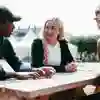 Three students sat on a bench on a sunny day.