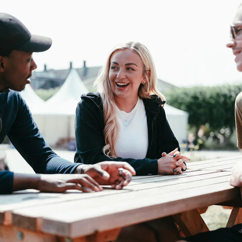Three students sat on a bench on a sunny day.