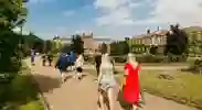 People walking on paths between lawns outside grand University of Hull building.