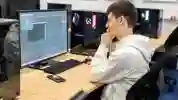 Student in grey hoodie sat working on a computer in the Turing Lab