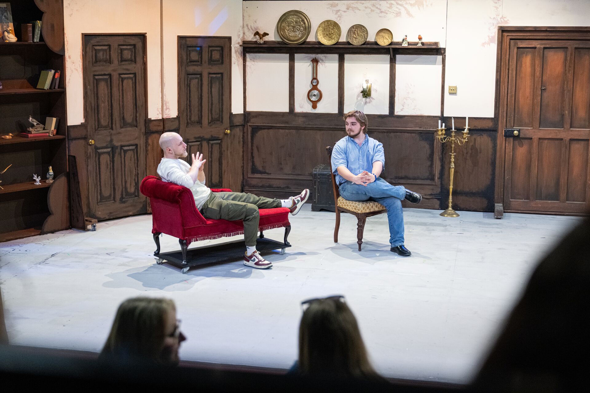 Two actors sat in armchairs on stage.