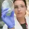 A student holding and looking through a petri dish