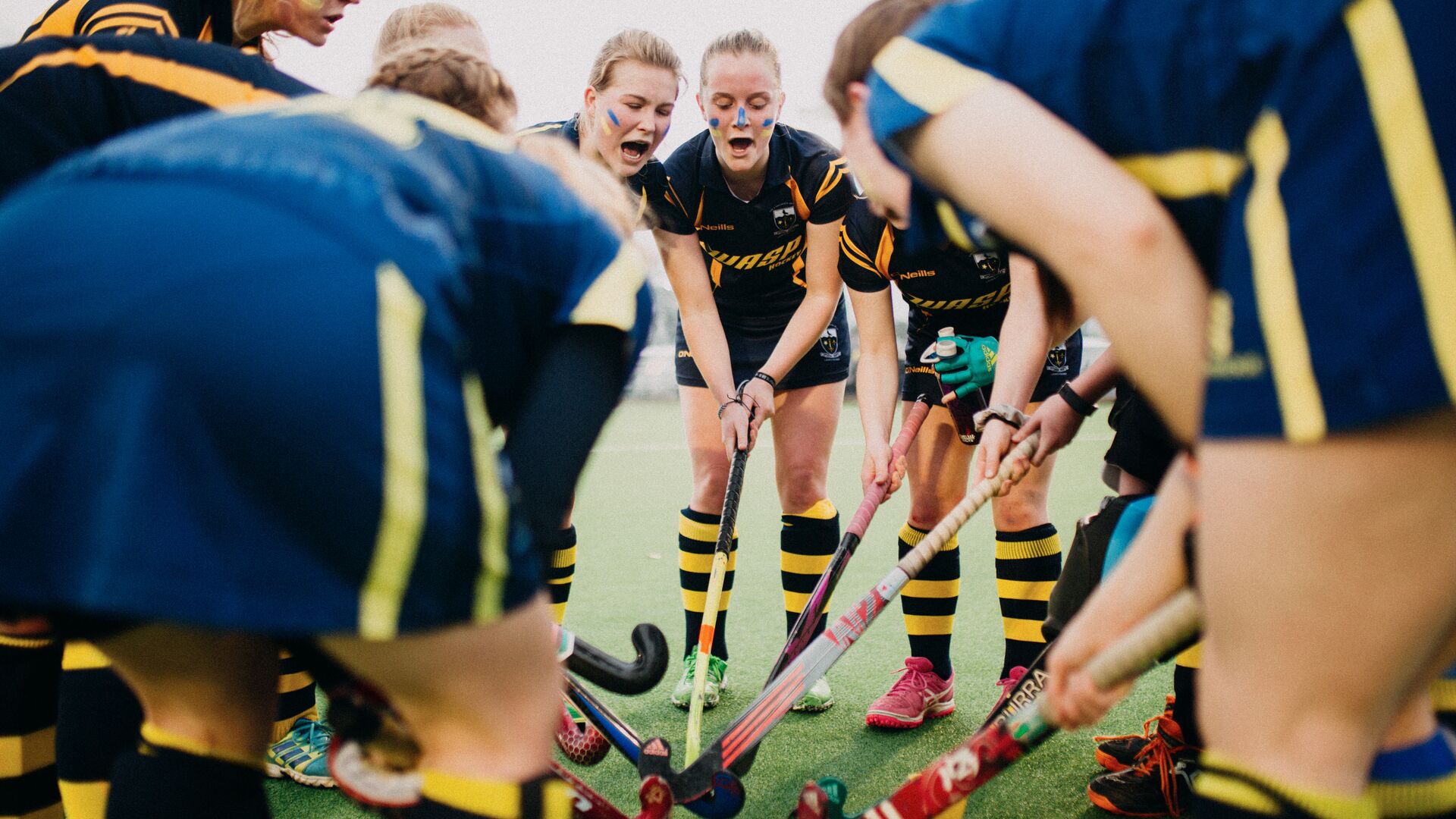 university women's hocky team pre-match huddle circle with sticks together