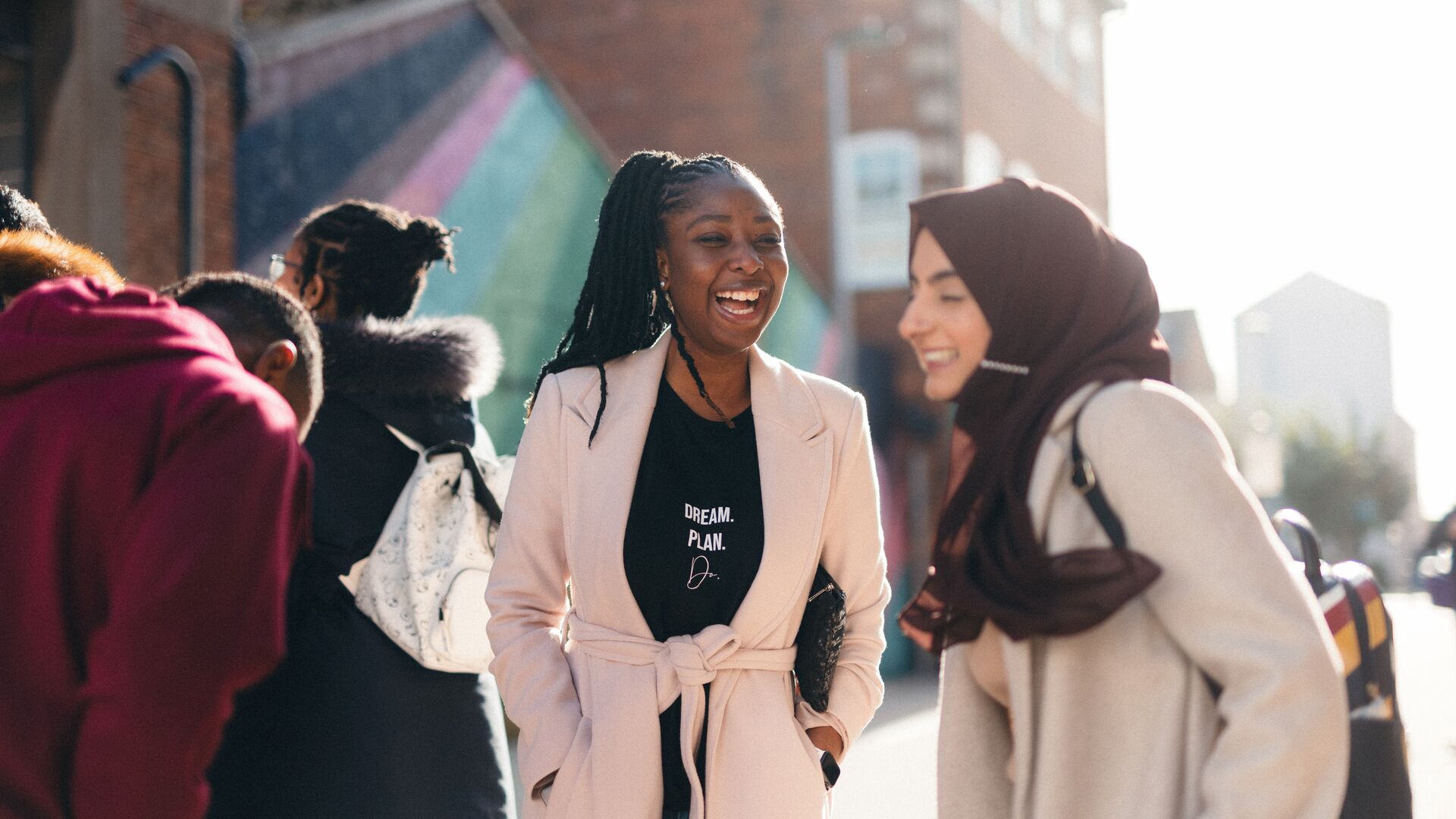 2 female international students laughing with each other on a sunny day