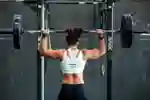 A woman lifts a heavy weight overhead in a gym