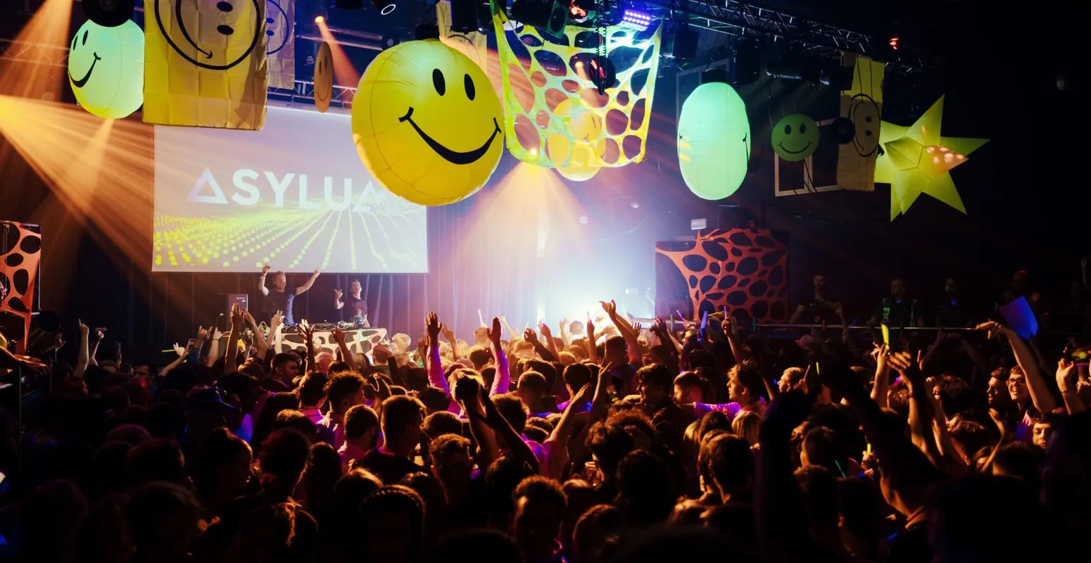 A large crowd parties underneath bright inflatables at our on-campus nightclub Asylum.
