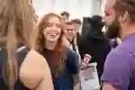 A female student smiles and laughs with friends at the Freshers Fair