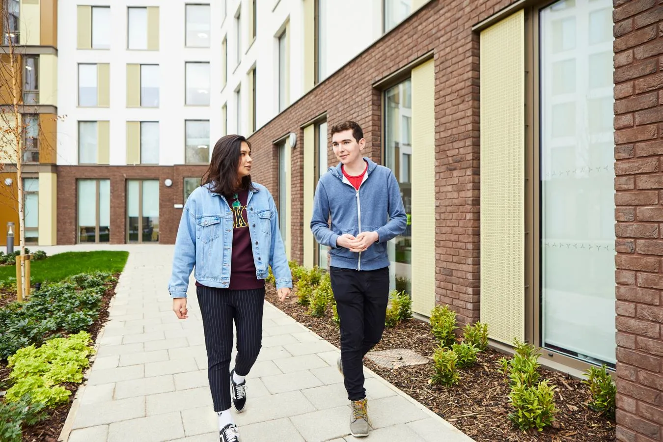 Two students chat while walking outside our modern Westfield Court accommodation blocks.