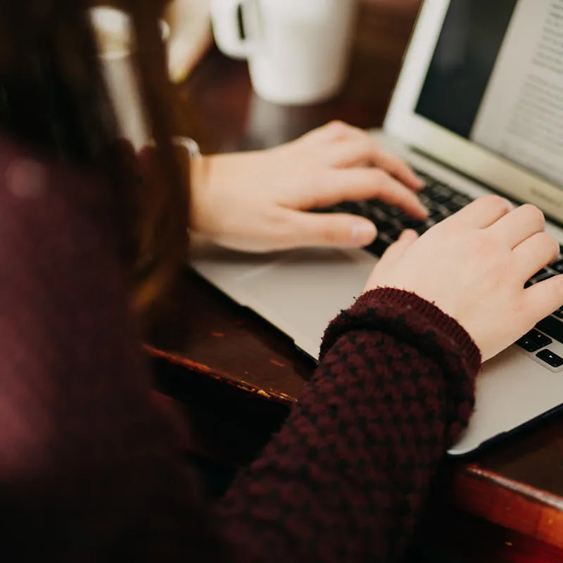A student working on an essay on their laptop.