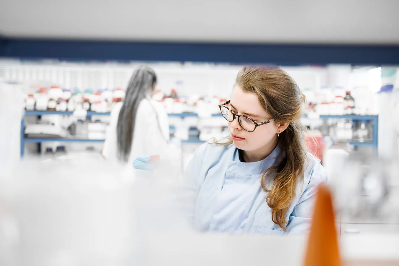 A female researcher inspects the contents of a vial in a laboratory