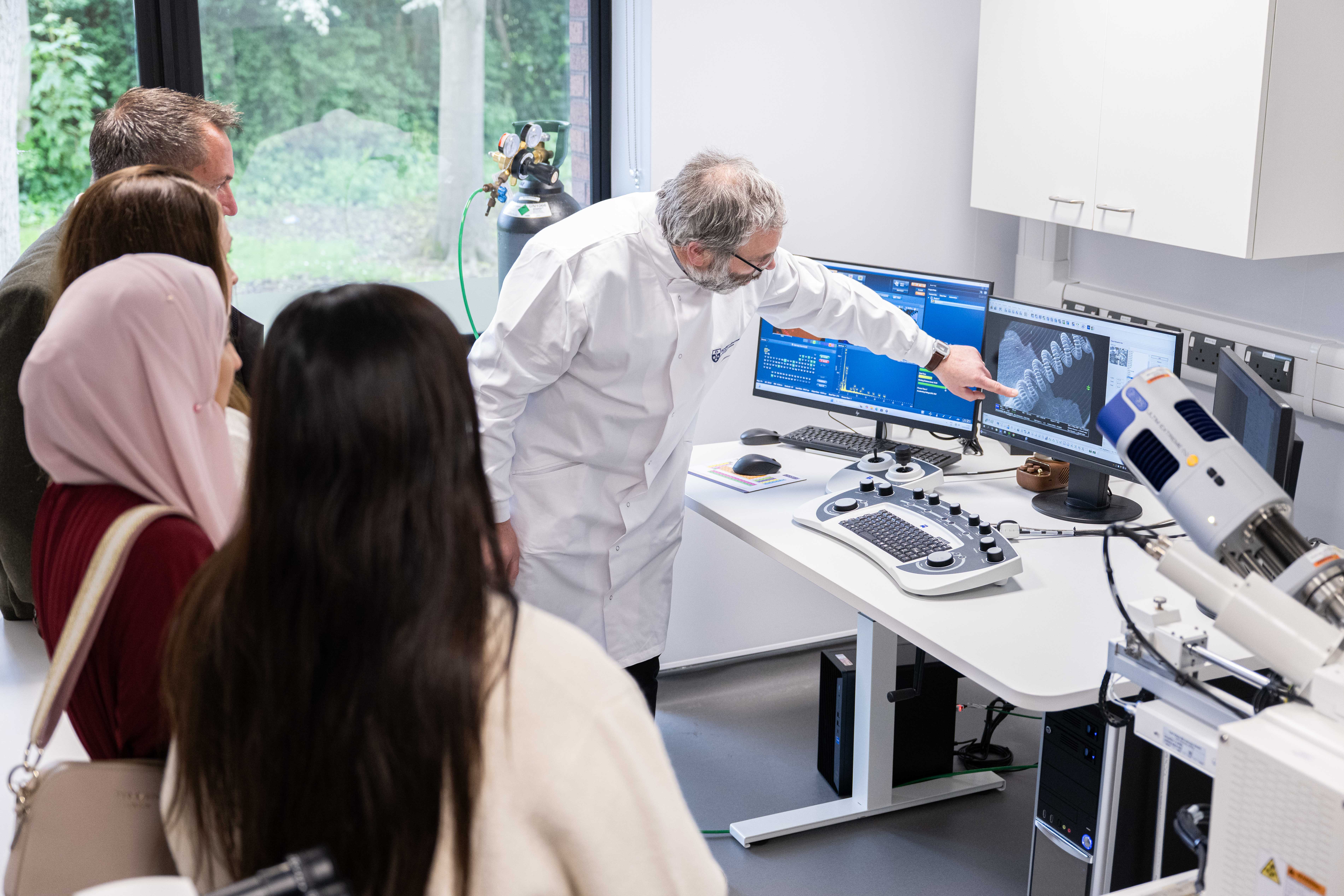 A researcher points to a 3D model on a screen relating to wound care, in front of a crowd of people