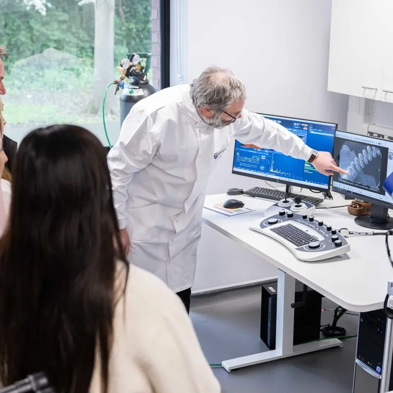 A researcher points to a 3D model on a screen relating to wound care, in front of a crowd of people