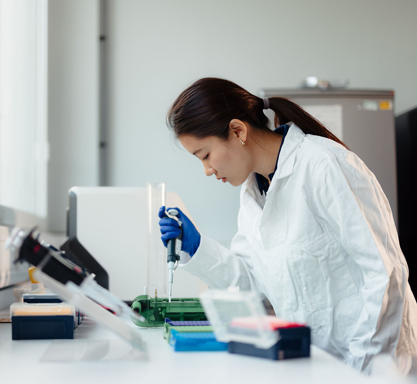 A student in lab coat using a pipette