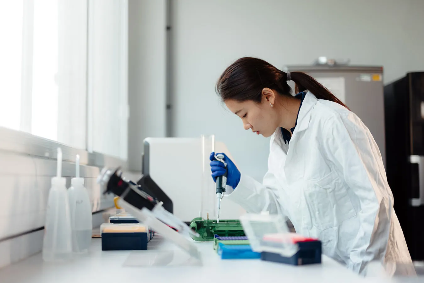 A student in lab coat using a pipette